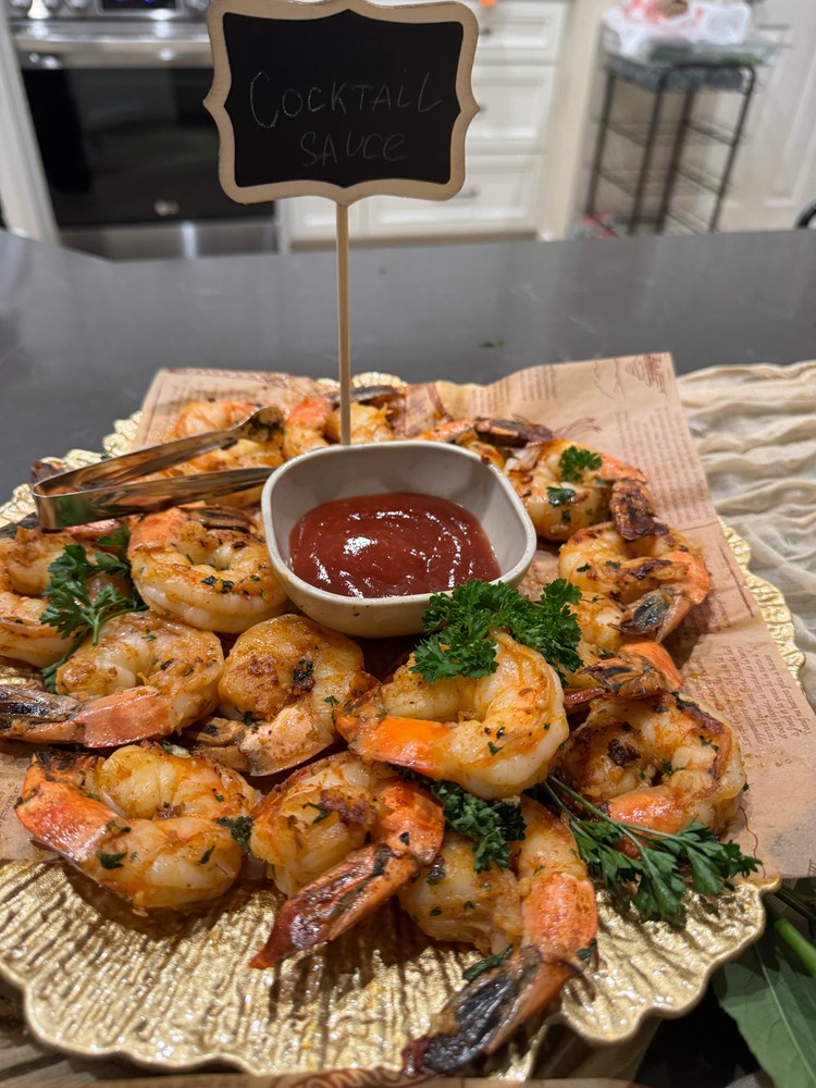 Garlic and herb shrimp with cocktail sauce on a golden platter