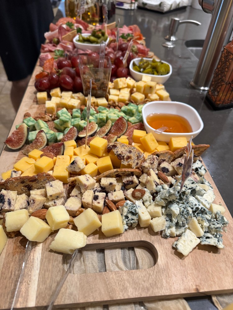 Cheese charcuterie board with various cheeses, figs, nuts, crackers, and honey