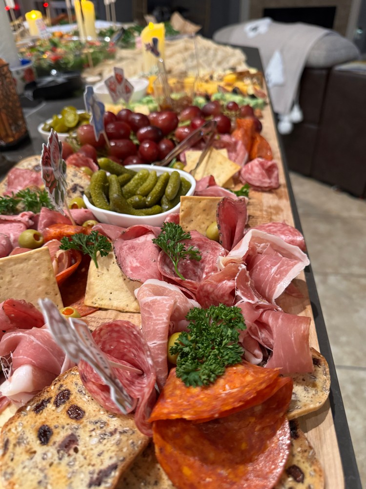 Meat charcuterie board with cured meats, crackers, pickles, and grapes