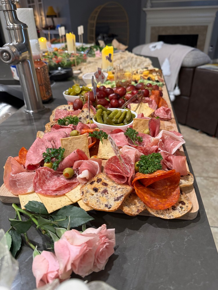 Meat charcuterie board with cured meats, crackers, pickles, and roses