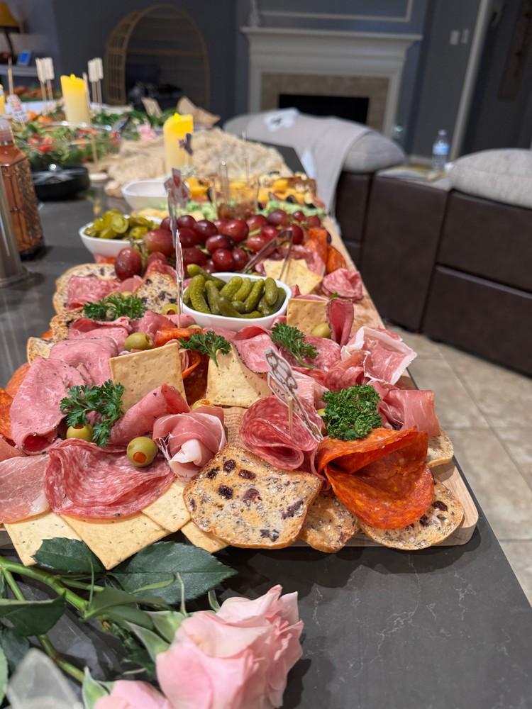 Meat charcuterie board with cured meats, crackers, pickles, and grapes