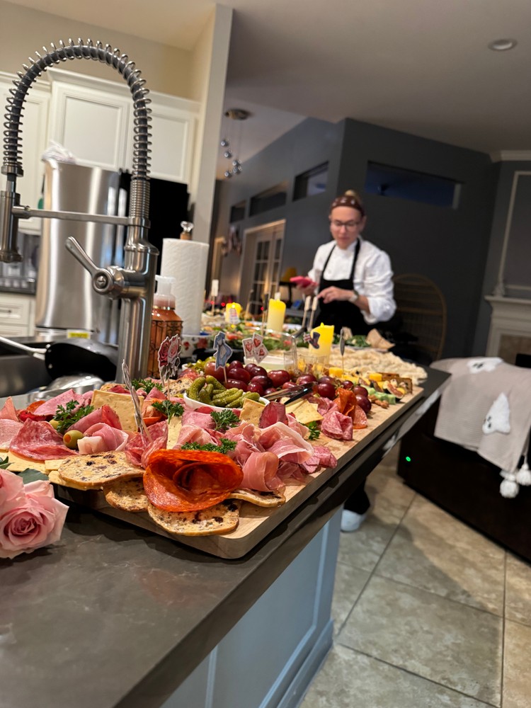 Chef Ana preparing charcuterie boards and other dishes in a home kitchen