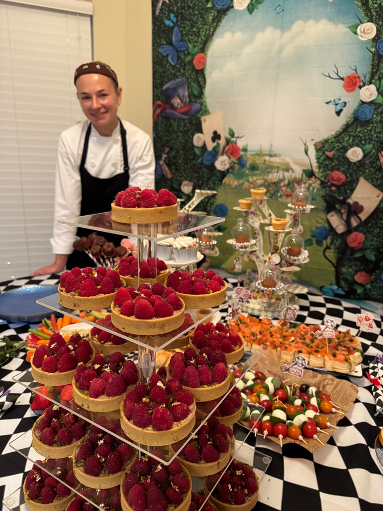 Chef Ana smiling with a dessert and appetizer buffet