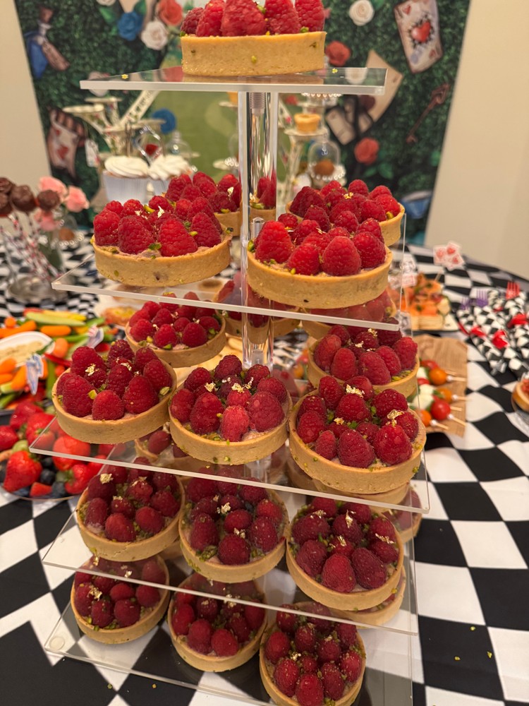 Tiered display of dairy-free mini chocolate tarts with raspberries