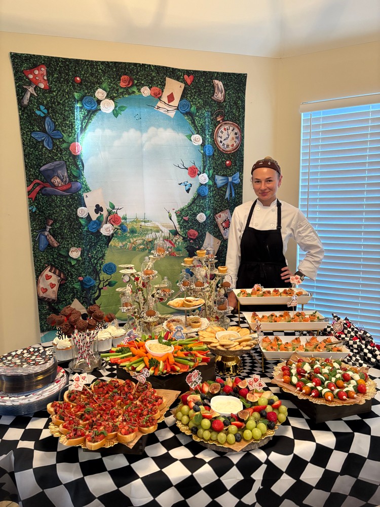Chef Ana proudly standing by a full buffet table