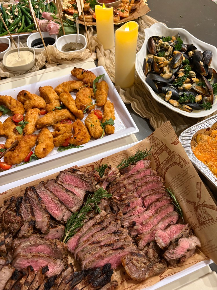 Buffet with sliced steak, chicken tenders, mussels, and mac & cheese