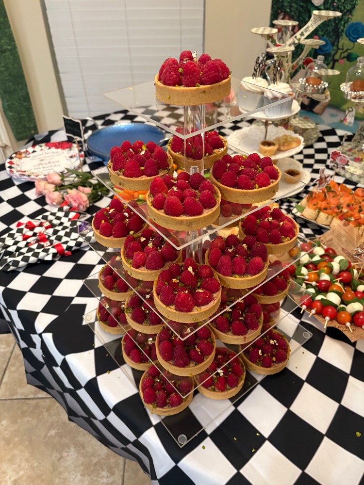 Dessert table with mini raspberry tarts, caprese skewers, and salmon puffs