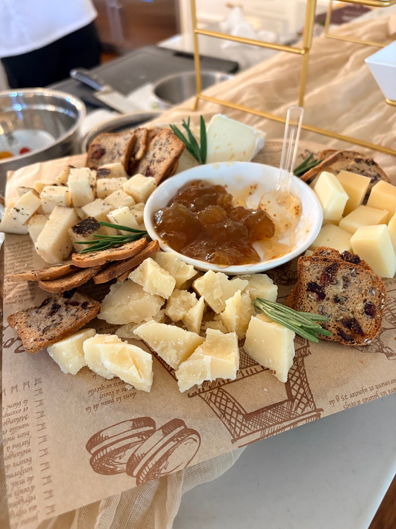 Cheese slices and cubes, crackers and preserves arranged on a wooden board at the appetizer counter.