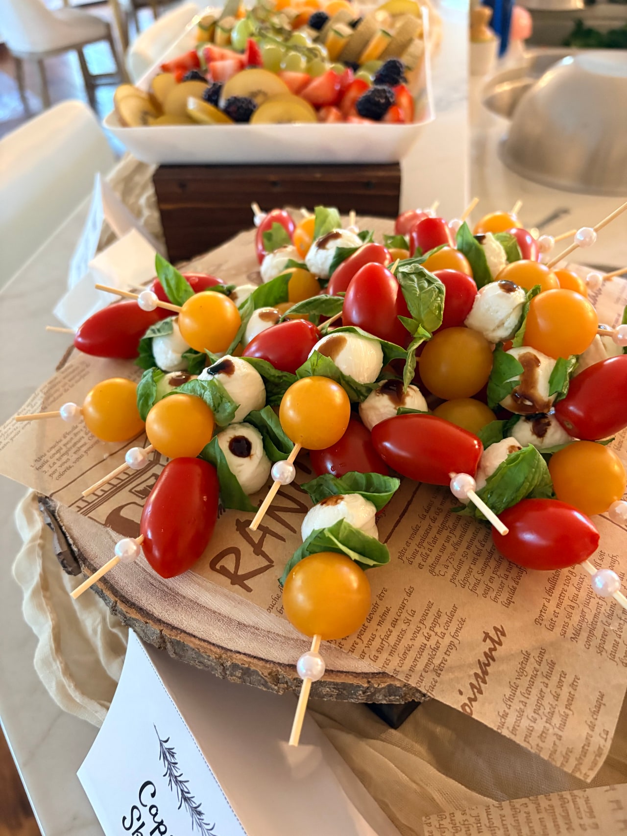 Skewers of mozzarella pearls, colorful cherry tomatoes and basil arranged on a serving platter.