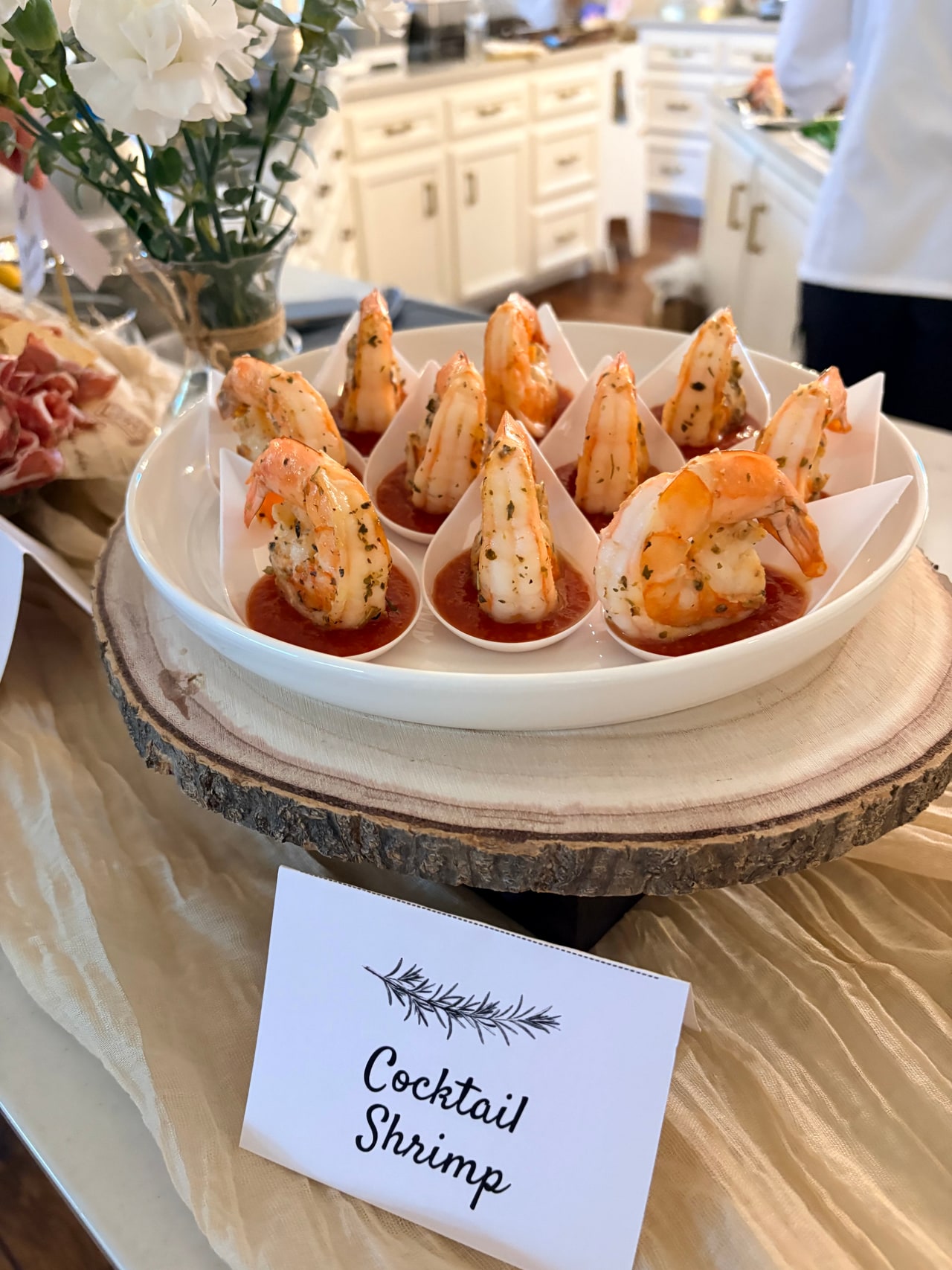 Cocktail shrimp in individual cups with lemon wedges on a tiered serving stand.