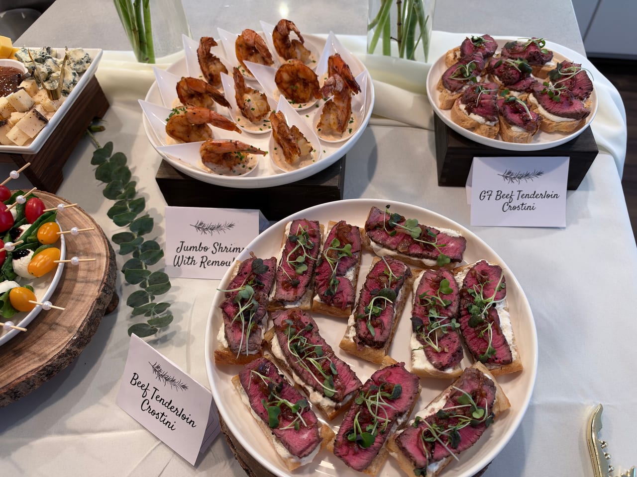 Overhead view of beef crostini, shrimp and colorful skewers on an appetizer table.