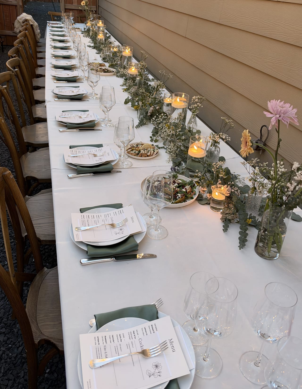 Candlelit birthday table seen from one end with place settings and dishes.