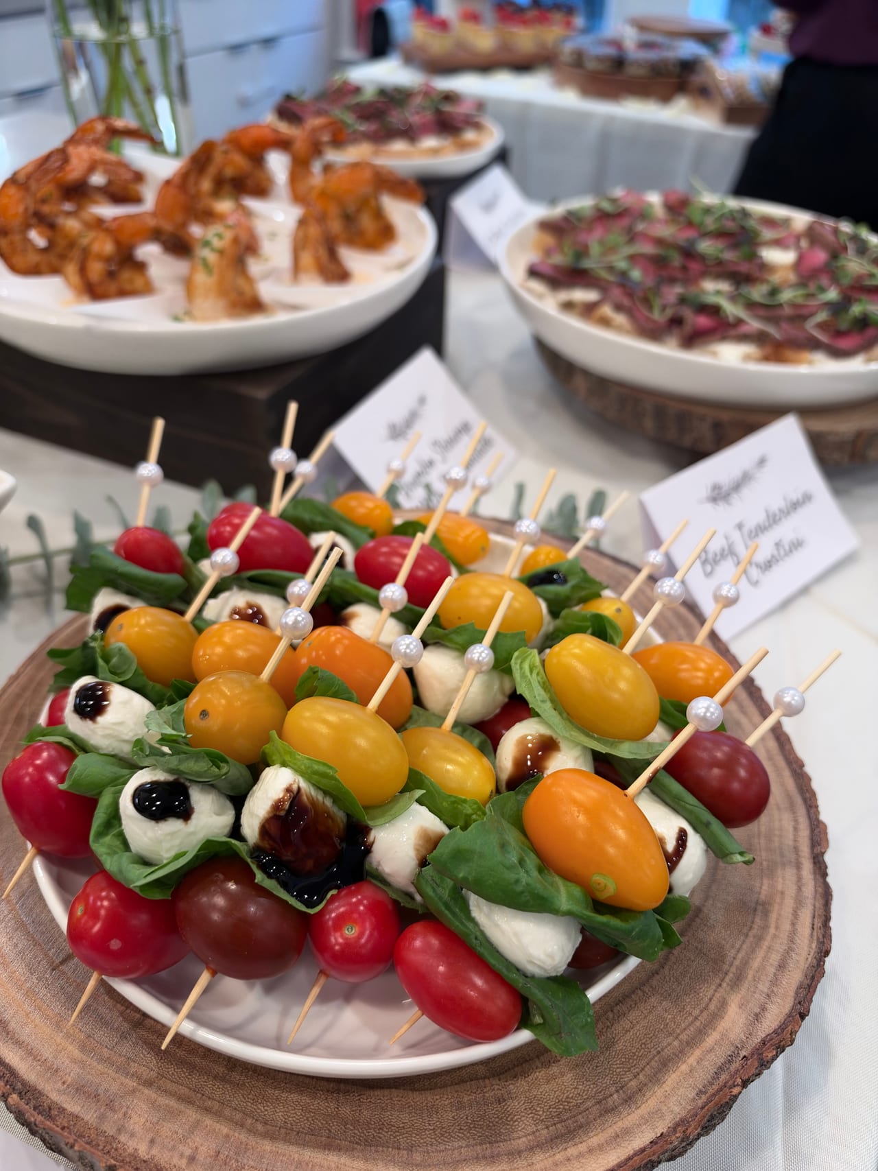 Tomato, mozzarella and melon skewers arranged on a round wooden board.
