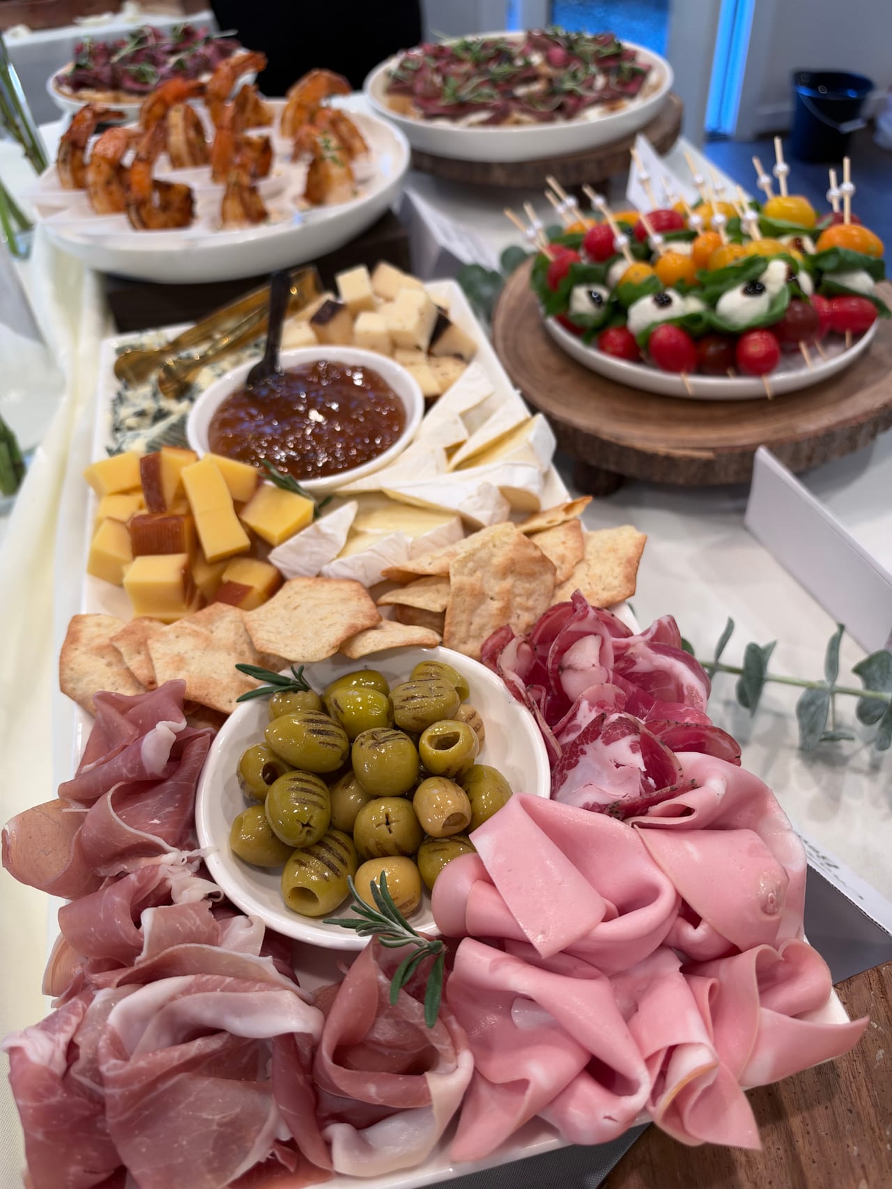 Cured meats, cheese, olives and crackers arranged on a wooden board.