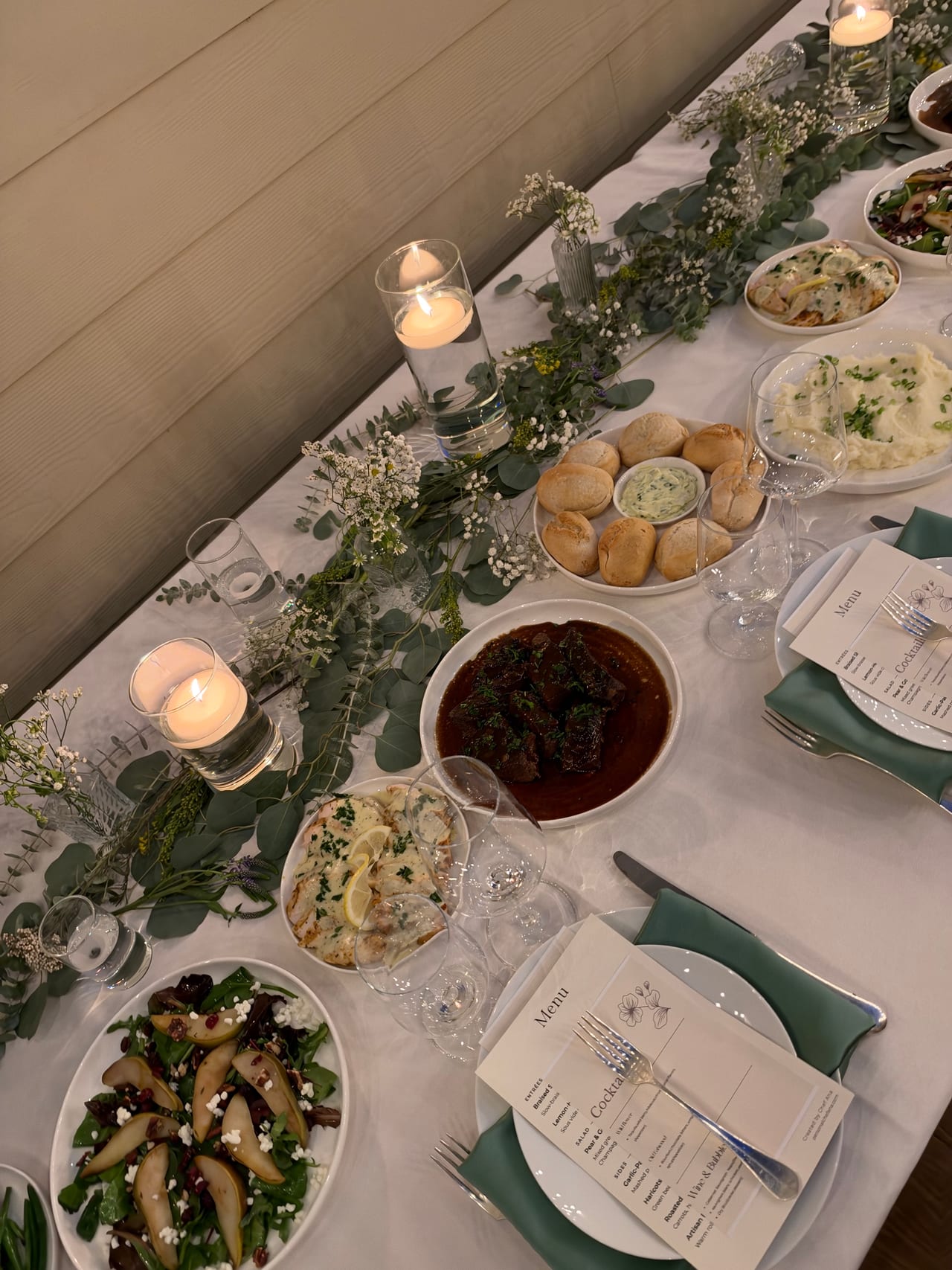 Pear salad and shared dishes on a candlelit dinner table.