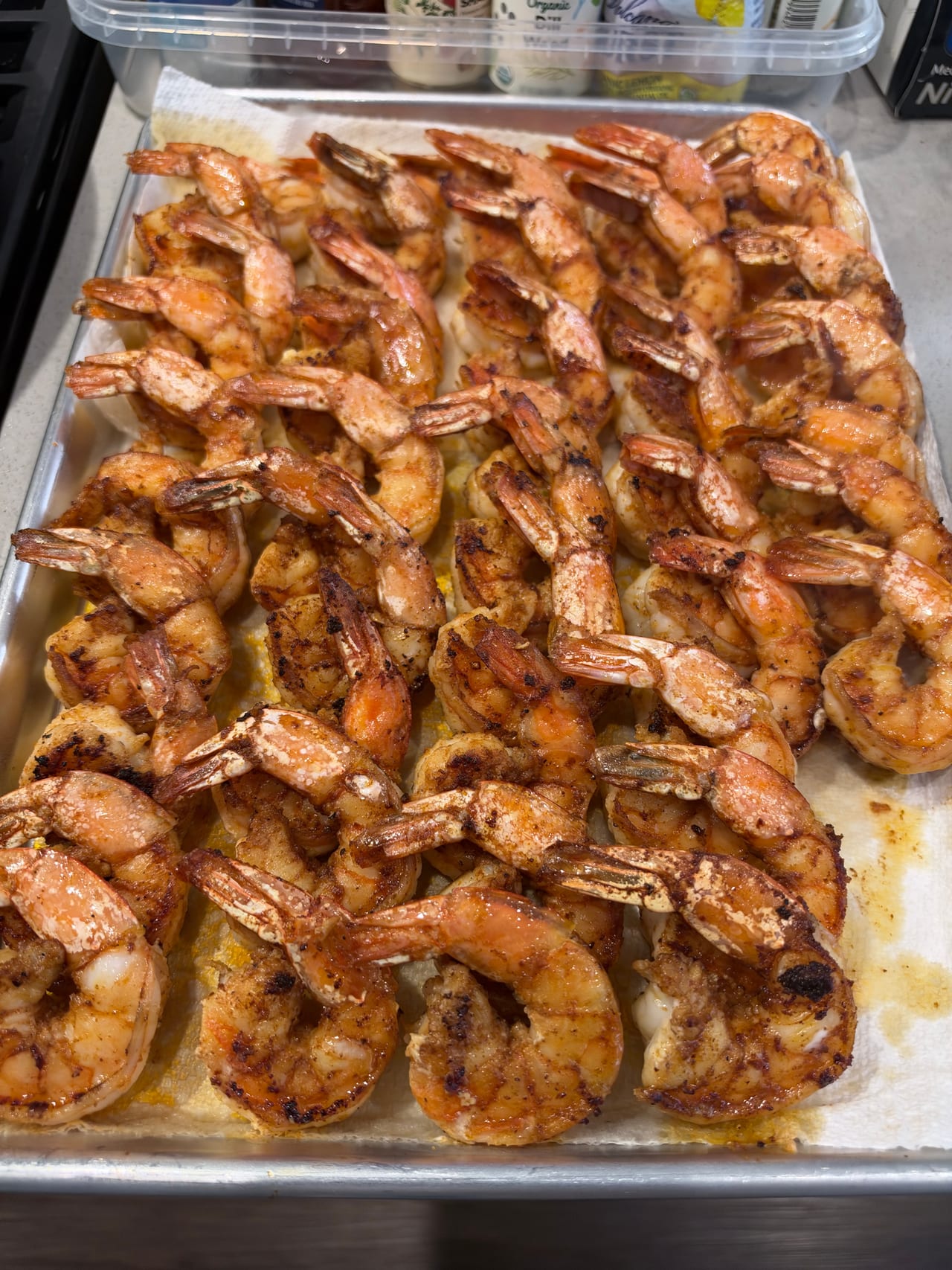 Cooked shrimp lined up on a metal tray before service.