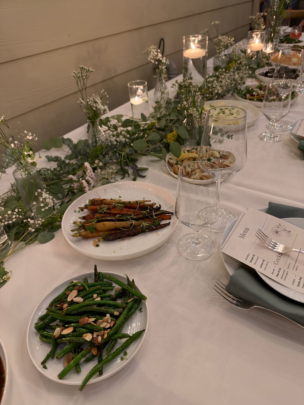 Green vegetables and other sides along a candlelit dinner table.