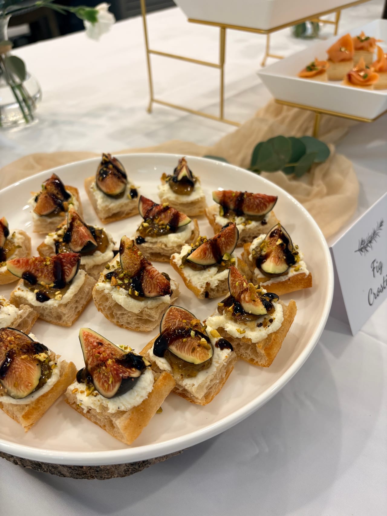 Fig crostini arranged on a white serving platter.