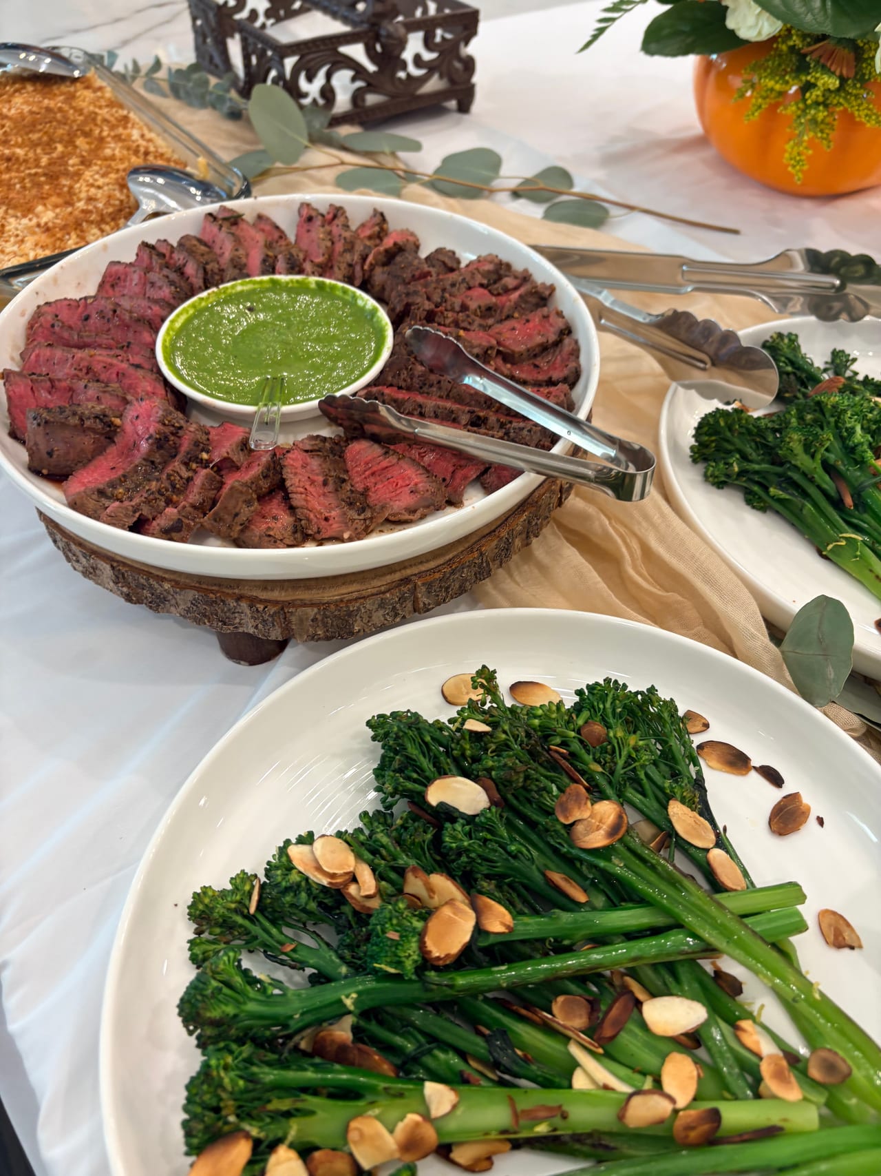 Sliced beef filet mignon with green sauce beside broccolini.