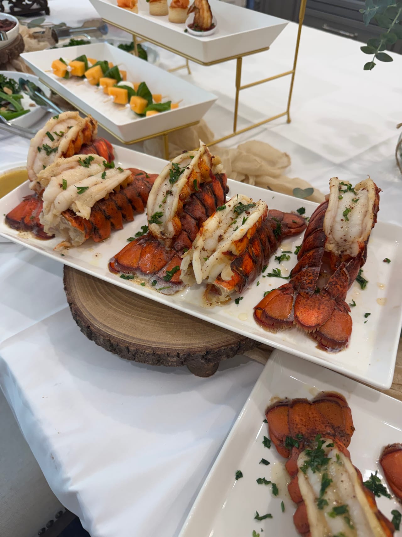 A closer view of lobster tails on a white serving board.