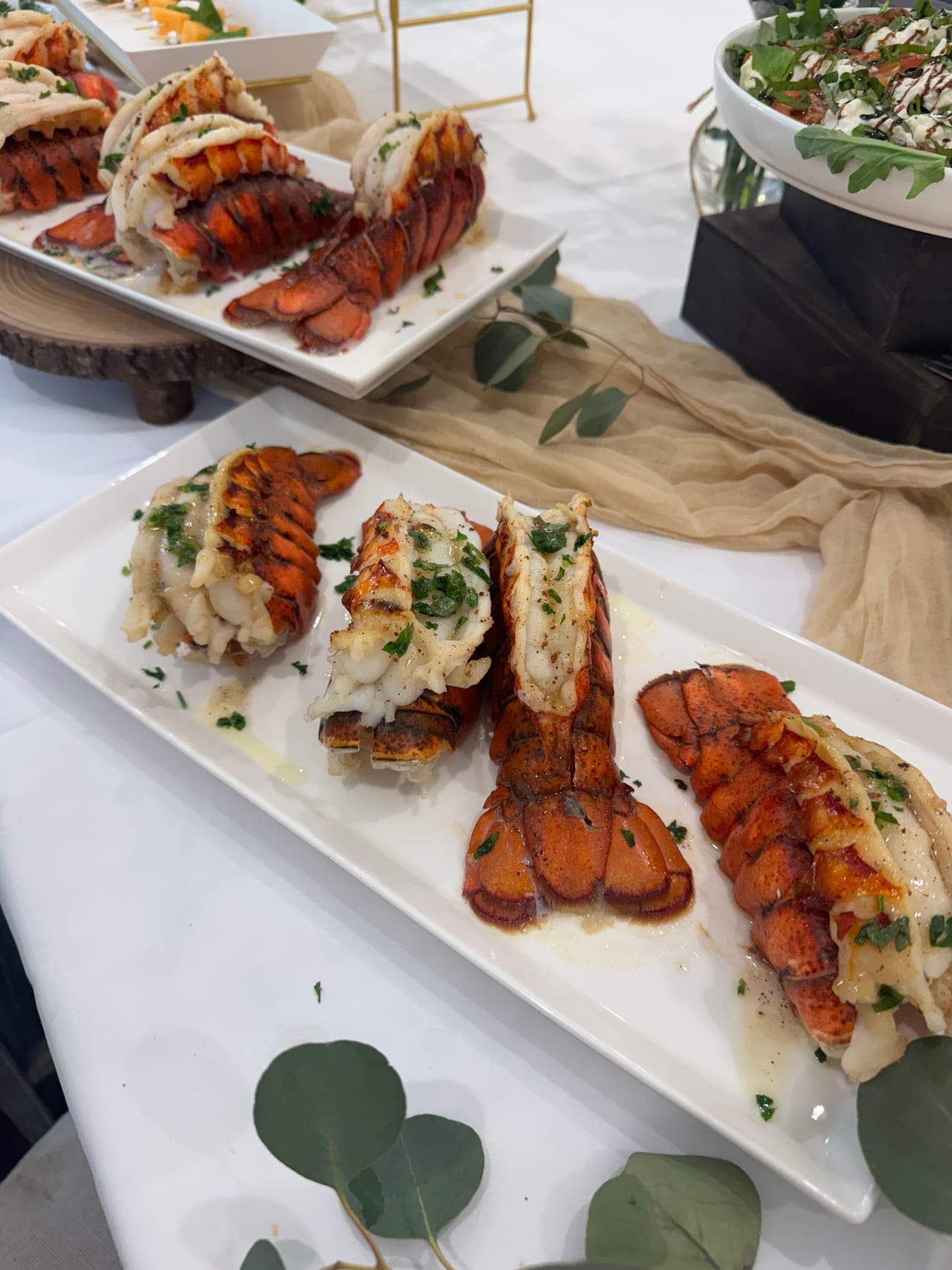 Lobster tails arranged on a rectangular white serving board.
