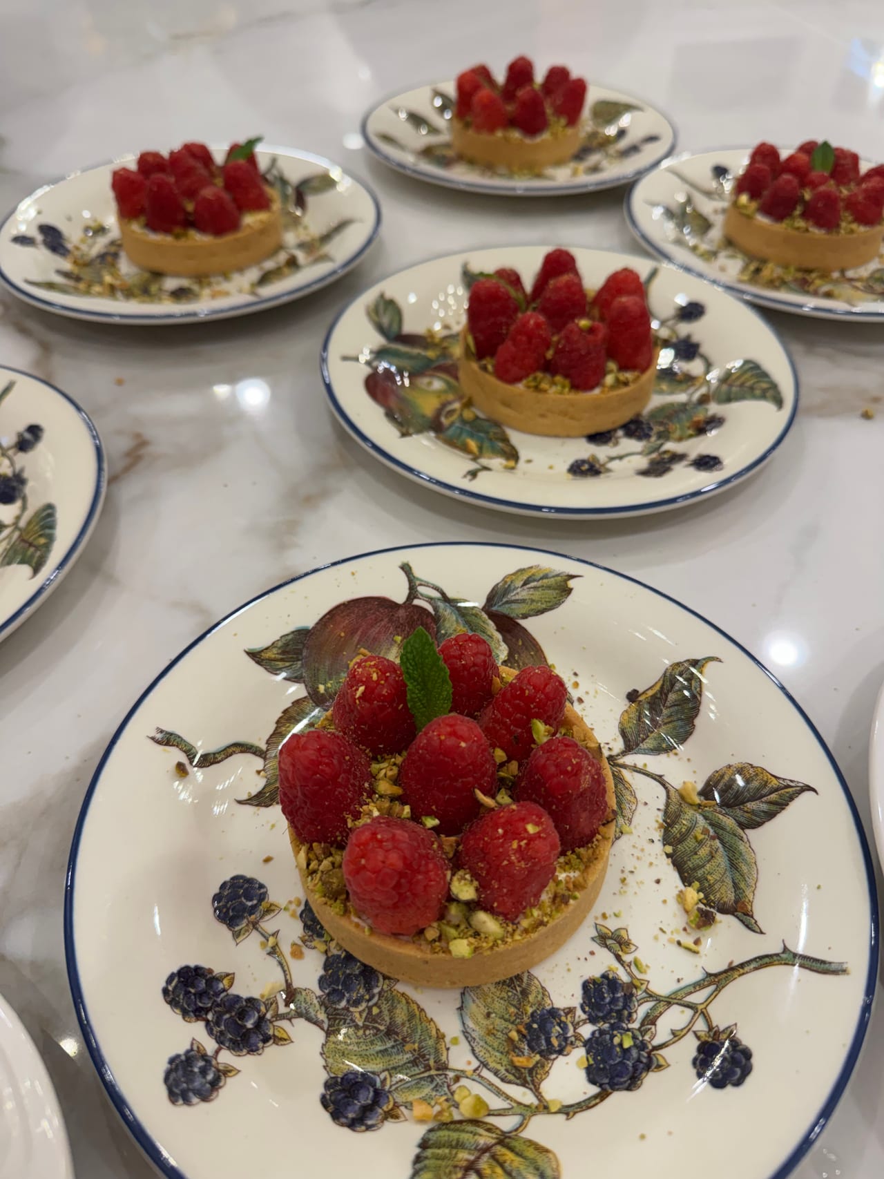 Individual raspberry cheesecake tartlets on decorated plates.