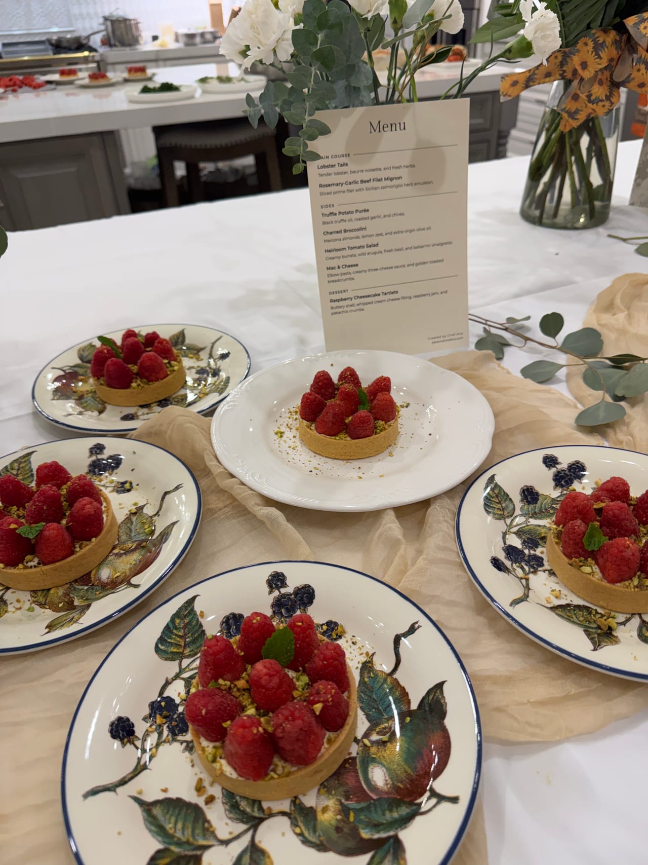 Raspberry tartlets around a printed dinner menu on the table.