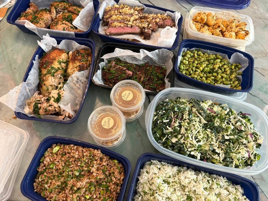 Arrangement of prepped meals including chicken, steak, farro, rice, edamame, and kale slaw.