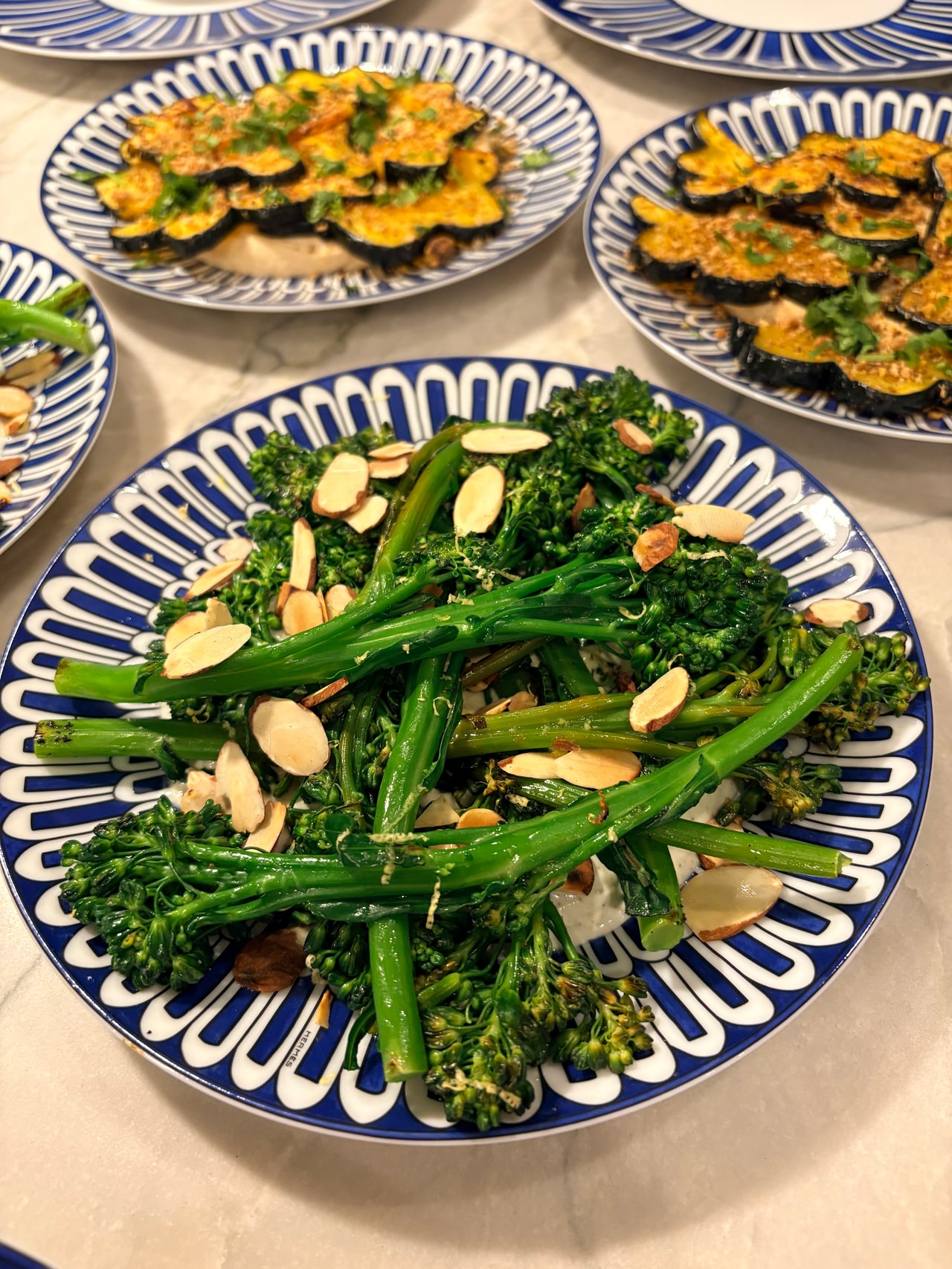 Broccolini and roasted acorn squash arranged on separate blue-and-white platters for dinner.