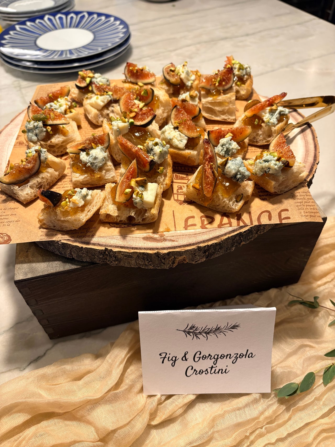 Fig and Gorgonzola crostini displayed on a wooden board with their menu label.