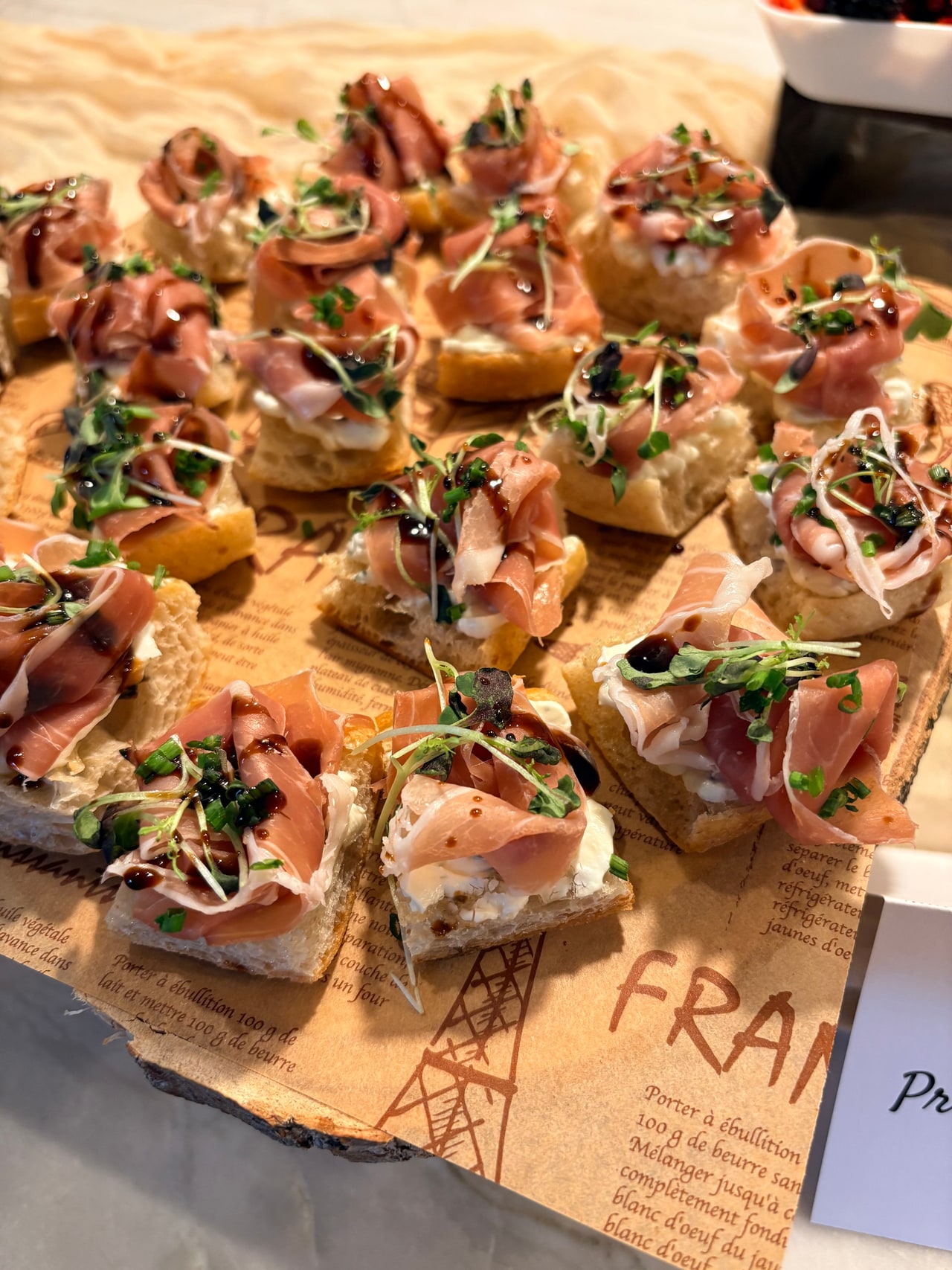 A close view of prosciutto folds, arugula and balsamic drizzle on toasted crostini.