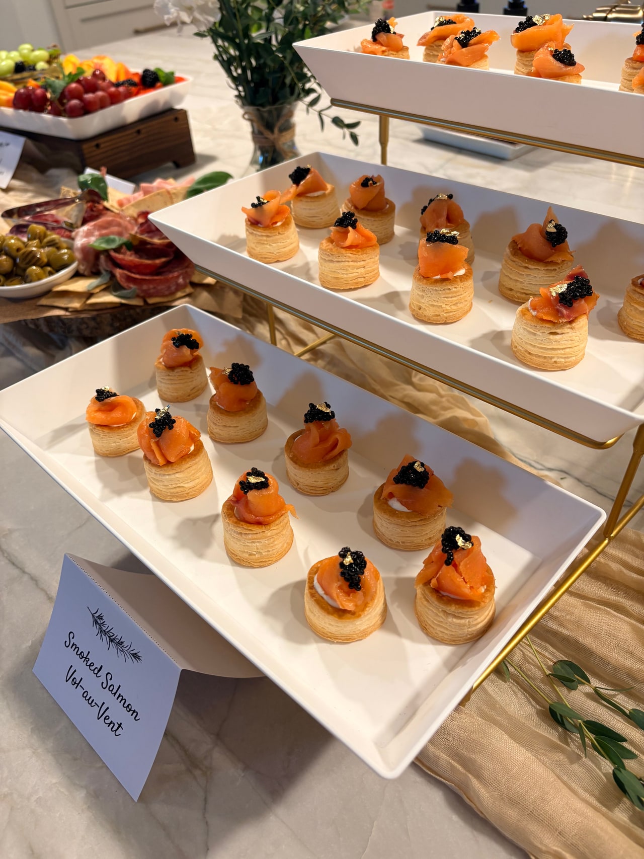 Smoked salmon vol-au-vents topped with caviar on a three-tier serving stand.