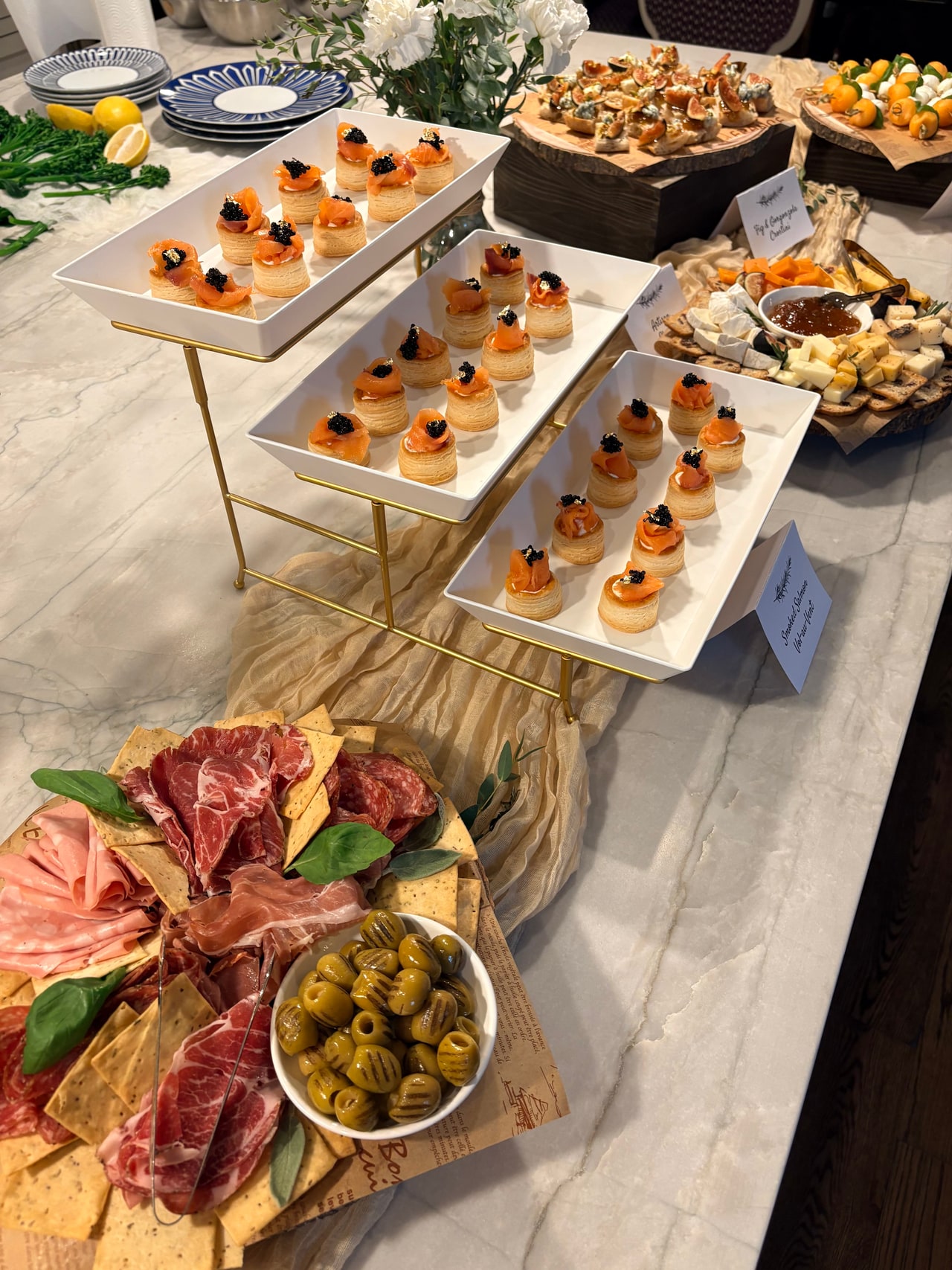 The appetizer counter with tiered salmon pastries, charcuterie, cheese, fruit and crostini.