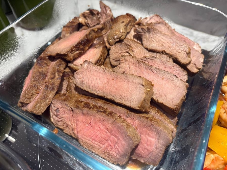 Sliced medium-rare steak in a glass dish.
