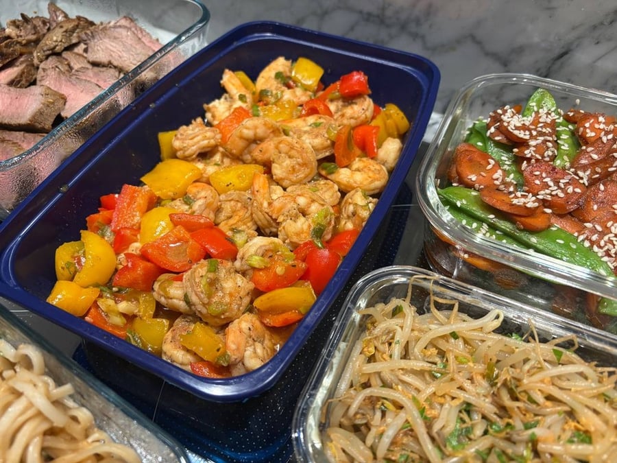 Shrimp and bell peppers stir-fry in a blue container.