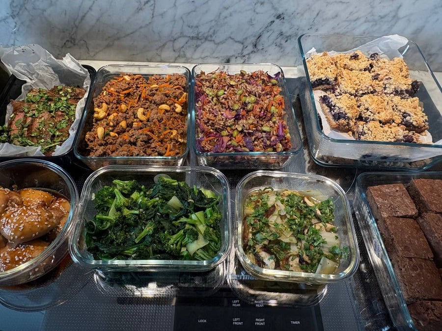 Wide shot of prepared meals, including proteins, vegetables, and desserts.