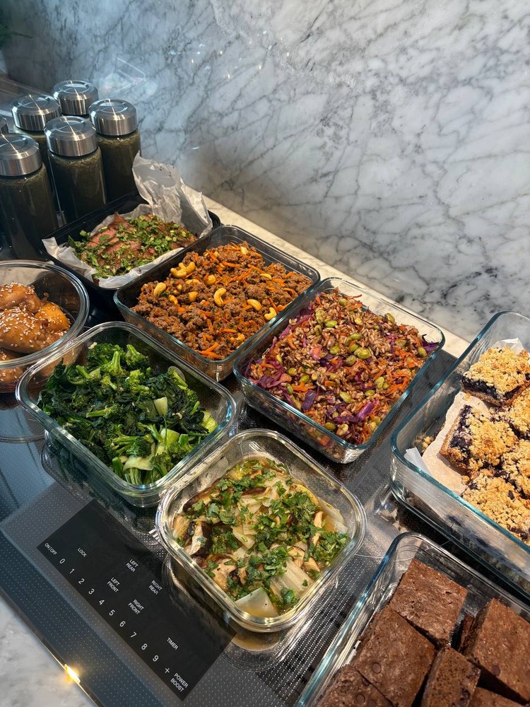 Full spread of meal prep containers with diverse dishes and green smoothies.